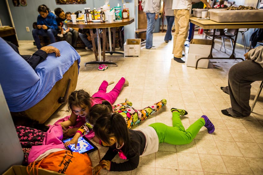Children play with an iPad at the feast celebrating Kaktovik's first whale of the year.